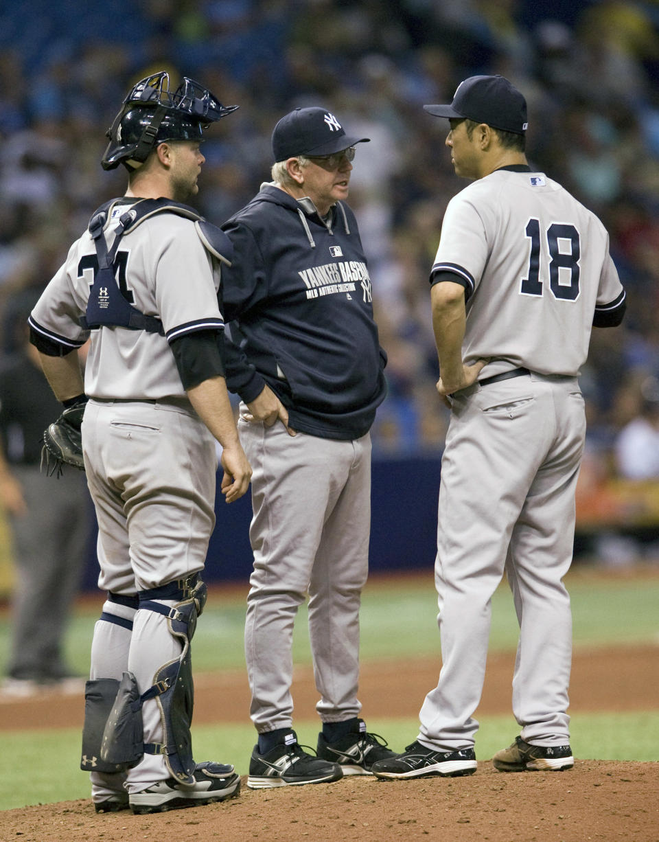 New York Yankees pitching coach Larry Rothschild, center, talks with catcher Brian McCann, left, and pitcher Hiroki Kuroda (18) during the sixth inning of a baseball game against the Tampa Bay Rays, Friday, April 18, 2014, in St. Petersburg, Fla. (AP Photo/Steve Nesius)