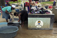 FILE - In this Thursday, March 4, 2021 file photo, women do laundry next to signs urging them to wear face masks to prevent the spread of COVID-19, at a farm on the outskirts of Harare, Zimbabwe. Official figures show that 4% of the country’s 15 million population are now fully immunized. The figures make Zimbabwe a relative success in Africa, where fewer than 2% of the continent’s 1. 3 billion people have been vaccinated, according to the World Health Organization. (AP Photo/Tsvangirayi Mukwazhi, File)