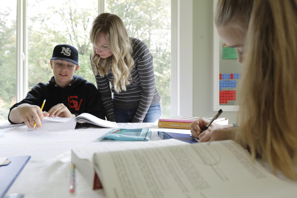 In this Oct. 9, 2019, photo, Donya Grant, center, works on a homeschool lesson with her son Kemper, 14, as her daughter Rowyn, 11, works at right, at their home in Monroe, Wash. The family joined a lawsuit against the Monroe School District and others, alleging that the district failed to adequately respond to PCBs, or polychlorinated biphenyls, at the Sky Valley Education Center, a K-12 public school. Grant has homeschooled her children since they left Sky Valley in 2016 for health reasons that they believe were related to the toxic chemicals. (AP Photo/Ted S. Warren)