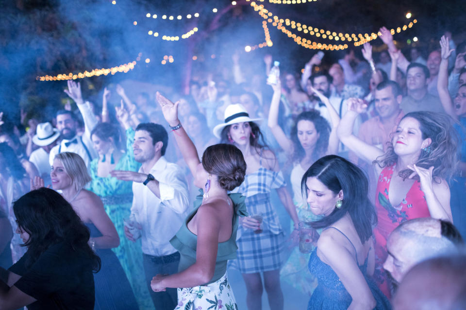 In this Feb. 16, 2019 photo, guests dance at the wedding party of Maria Fernanda Vera and Juan Jose Pocaterra in La Llanada, a summer camp at the Camburito Hacienda in Acarigua, Venezuela. Johnnie Walker Black scotch whiskey flowed as guests lined up for a buffet of beef, pork and yucca. (AP Photo/Rodrigo Abd)