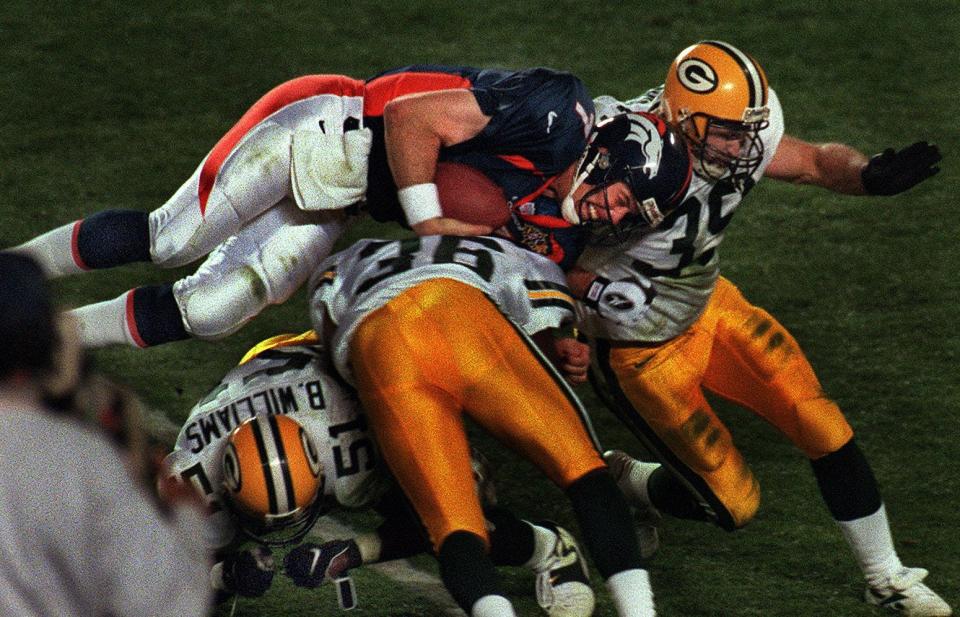 Denver quarterback John Elway dives over Green Bay Packer defenders in the third quarter of the Super Bowl on January 25, 1998, in San Diego.