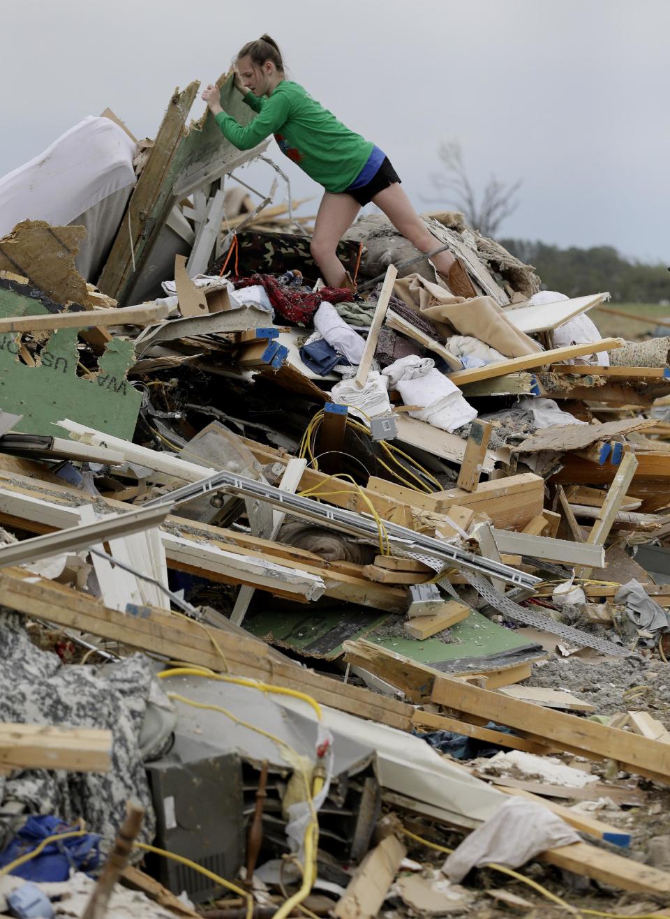 Callie Moore looks through the debris of her home that was destroyed by Sunday's tornado, Tuesday, April 29, 2014, in Vilonia, Ark. A dangerous storm system spawned a chain of deadly tornadoes over three days. (AP Photo/Eric Gay)