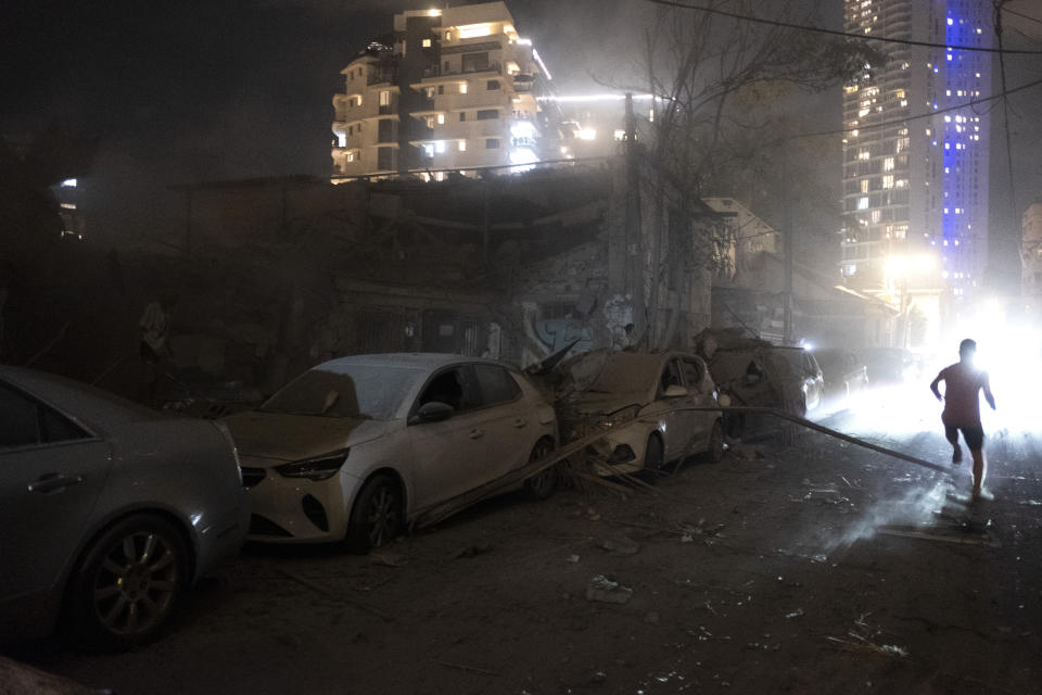 People walk by the damage from a rocket fired from the Gaza Strip in Tel Aviv, Israel, Saturday, Oct. 7, 2023. (AP Photo/Moti Milrod) ***ISRAEL OUT***