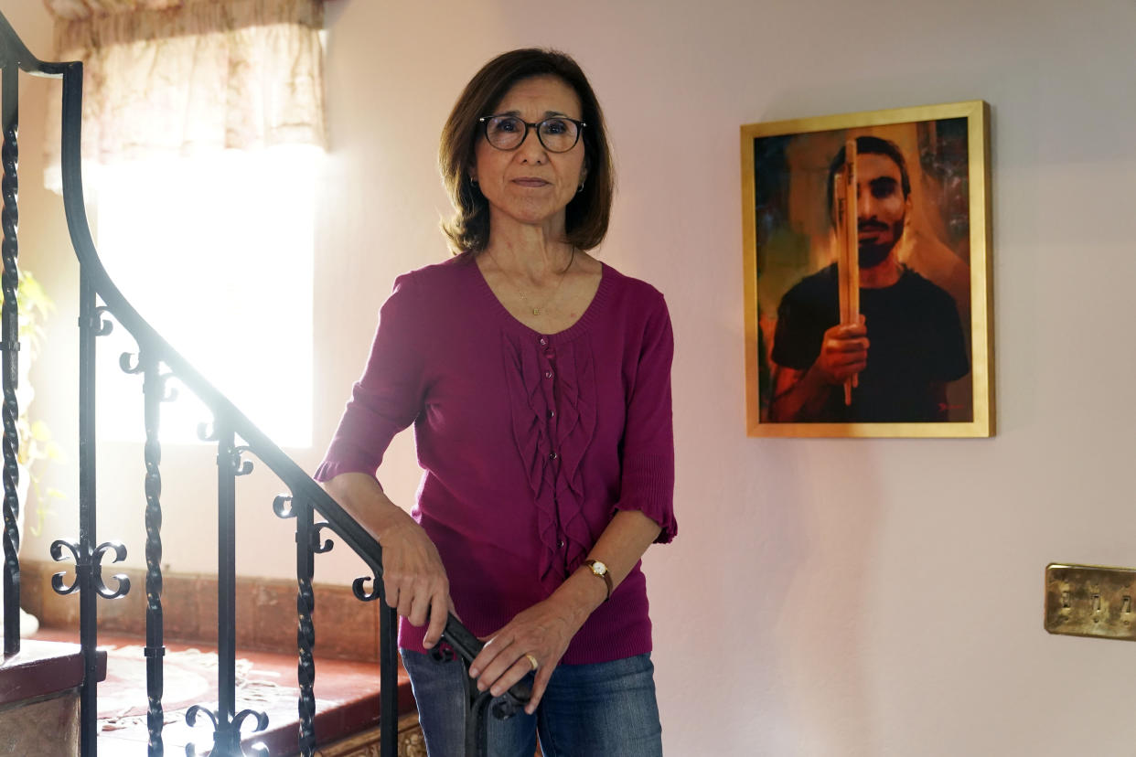 Dolores Cruz poses next to a painting of her youngest son, Eric Cruz, on Wednesday, Feb. 1, 2023, at her home in San Gabriel, Calif. Cruz published an essay in 2022 about grieving for her son, who died in a car crash in 2017. "Died Suddenly" used a screenshot of the headline in the film, portraying his death as vaccine related. (AP Photo/Marcio Jose Sanchez)