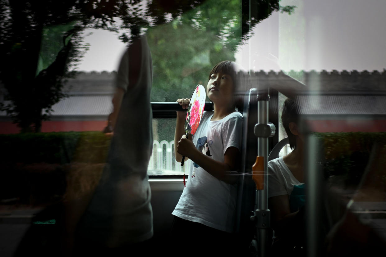 A girl holds fan while riding a bus during a summer day in Beijing (Wang Zhao / AFP via Getty Images file)