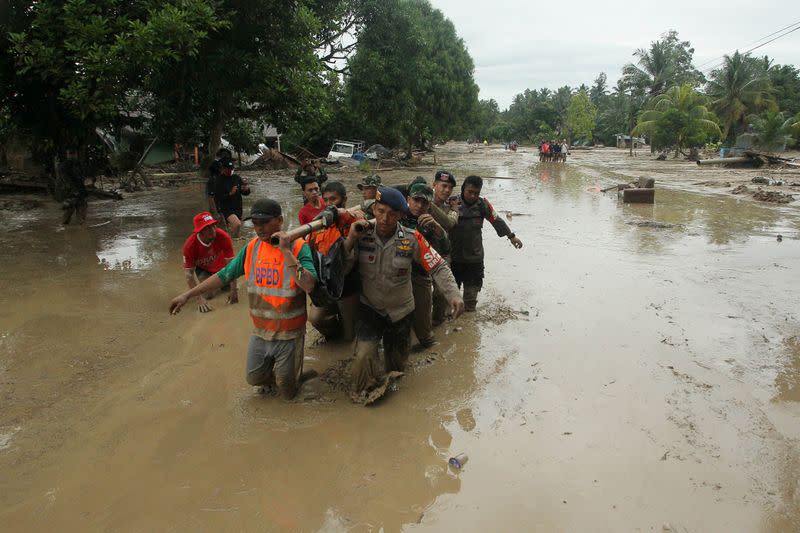 Officers evacuate victims in Radda Village, following flash floods that left several dead and dozens remain missing, in North Luwu in Sulawesi