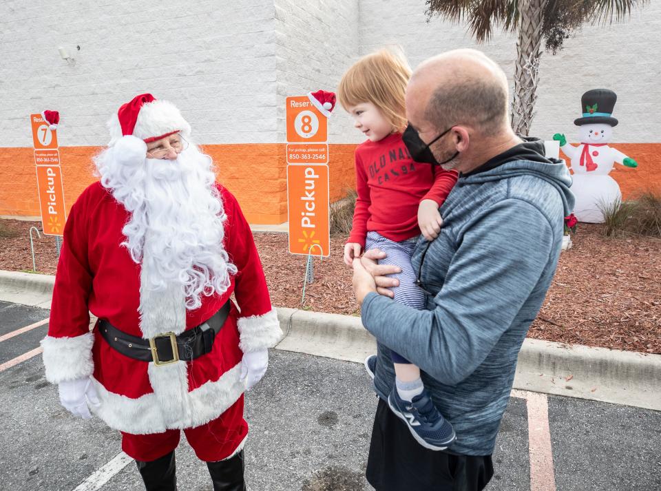 The Walmart store on Panama City Beach Parkway treated one of their pick up order customers Friday with a Christmas surprise. Alan and Anais Bearden, and their son Bennett, were greeted by Santa and his elves when they arrived to get their order. Walmart gave them their order for free and included a one year Walmart+ membership in the surprise. In the photo Alan holds his son, Bennett, as he gets a little time with Santa.