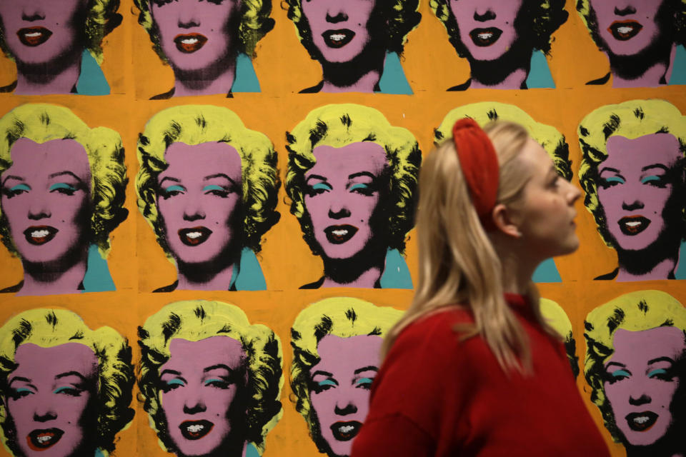 CAPTION CORRECTS NAME OF ARTWORK A Tate representative poses for photographs next to the 1962 Andy Warhol piece“Marilyn Diptych”, during a media preview for the exhibition "Andy Warhol" at the Tate Modern gallery in London, Tuesday, March 10, 2020. The exhibition, which runs from March 12 to September 6, features over 100 works spanning the American artist's career in the second half of the 20th century until his death in 1987. (AP Photo/Matt Dunham)