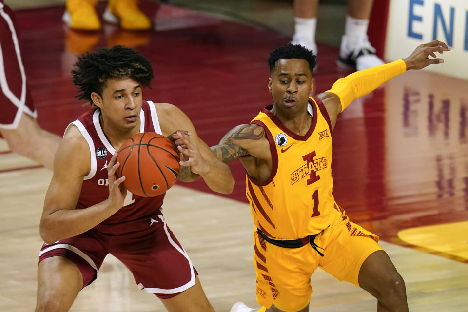 Oklahoma forward Jalen Hill passes ahead of Iowa State guard Tyler Harris, right, during the second half of an NCAA college basketball game, Saturday, Feb. 20, 2021, in Ames, Iowa. Oklahoma won 66-56. (AP Photo/Charlie Neibergall)