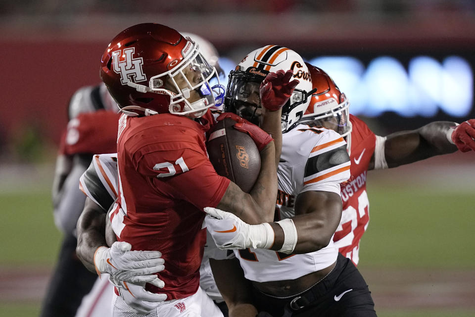 Houston running back Stacy Sneed (21) is hit by Oklahoma State safety Nick Session (14) while returning a kick during the second half of an NCAA college football game Saturday, Nov. 18, 2023, in Houston. Oklahoma State won 43-30. (AP Photo/David J. Phillip)
