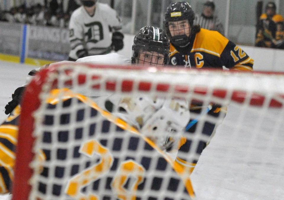 Duxbury's Wyatt Glass watches his shot go past Hanover goalie Liam Monahan, foreground, as Duxbury's Robbie Hanna, right, moves in during boys hockey at The Bog in Kingston on Monday, Jan. 31, 2022.