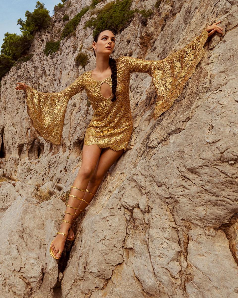 a woman in a yellow dress sitting on a rock