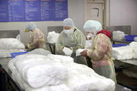 Workers package medical masks in a factory in Nantong in eastern China's Jiangsu Province, Monday, Jan. 27, 2020. China on Monday expanded sweeping efforts to contain a viral disease by extending the Lunar New Year holiday to keep the public at home and avoid spreading infection. (Chinatopix via AP)