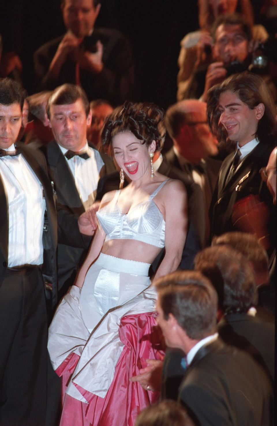 Madonna wears a white bra, matching shorts, and a pink robe at the 1991 Cannes Film Festival.