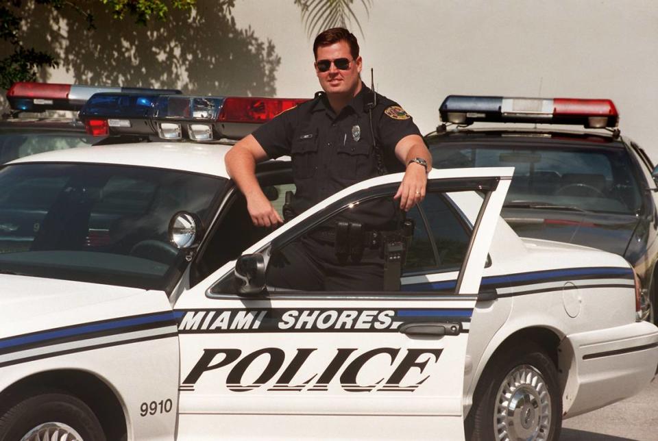 A Miami Shores police officer shows off a new white car that replaced a fleet of purple ones in 1999.