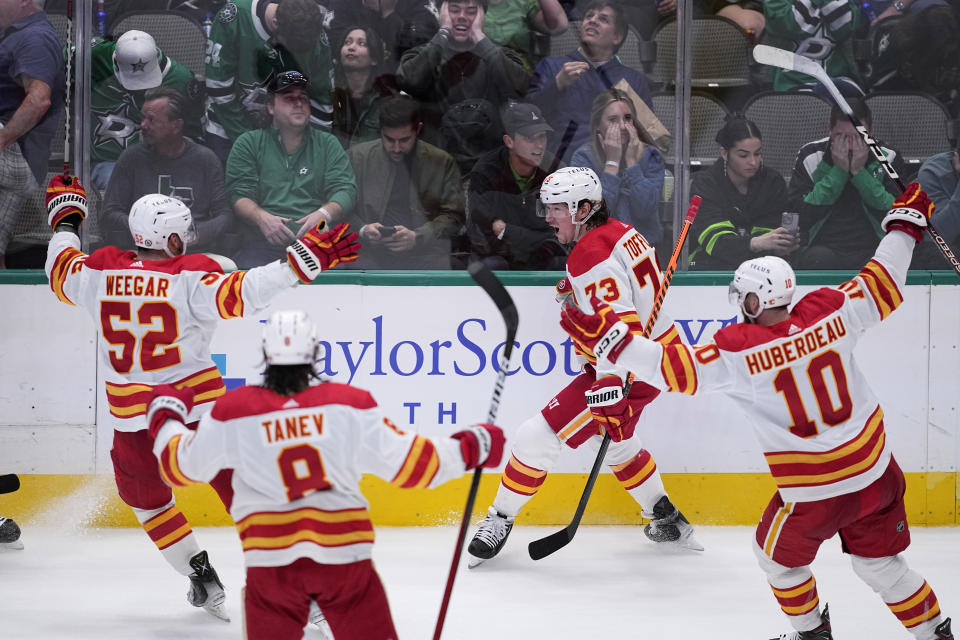 Calgary Flames right wing Tyler Toffoli (73) celebrates with MacKenzie Weegar (52), Chris Tanev and Jonathan Huberdeau (10) after scoring in the final seconds of the third period of an NHL hockey game against the Dallas Stars, Monday, March 6, 2023, in Dallas. (AP Photo/Tony Gutierrez)