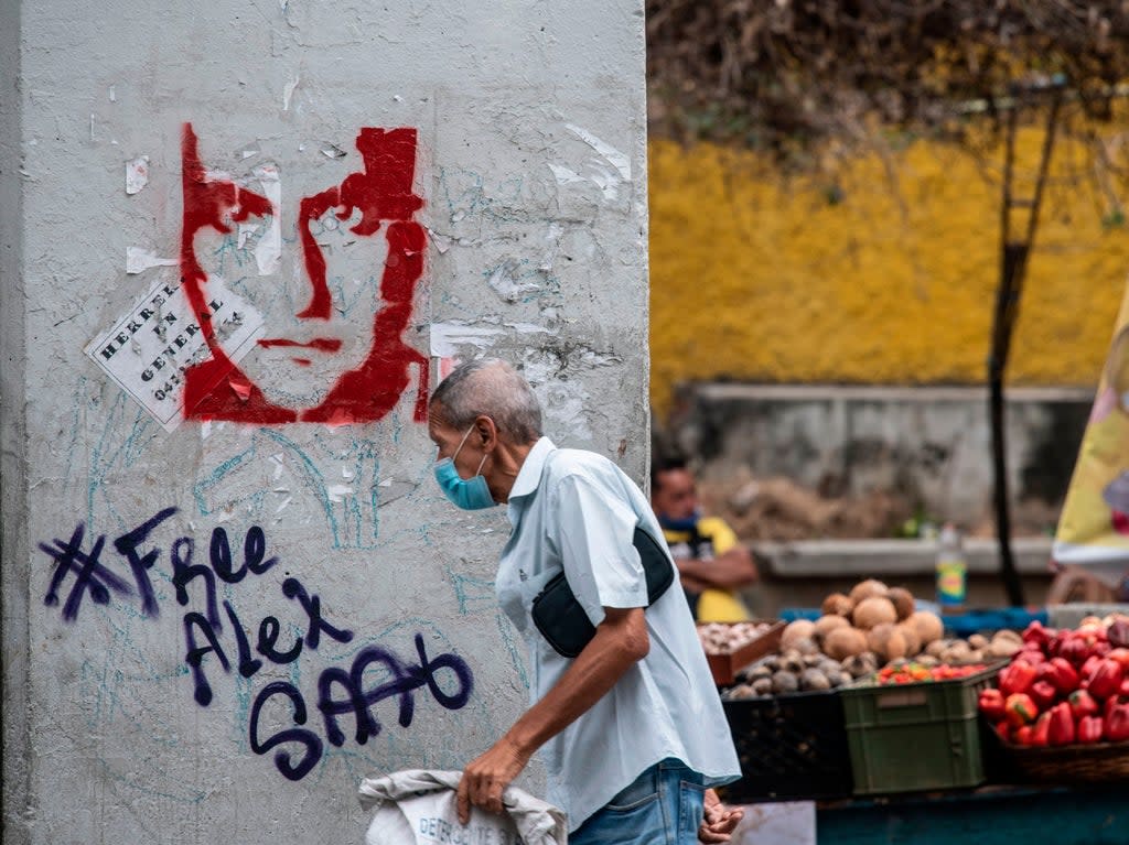 A man walks past graffiti in Caracas demanding Colombian businessman Alex Saab’s freedom (Yuri Cortez/AFP via Getty Images)