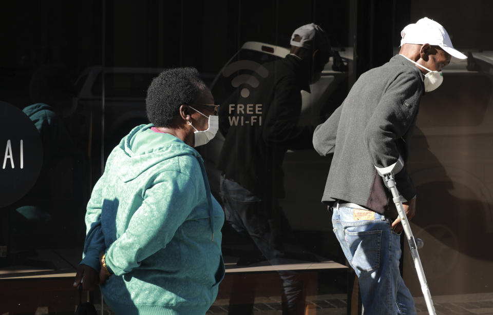 People wearing face masks queue at a South African Social Security Agency (SASSA) to collect their government grant in Cape Town South Africa, Monday, May 11, 2020. South Africa's Western Cape province, which includes the city of Cape Town, has emerged as the country's coronavirus hotspot, accounting for more than half of the nation's confirmed cases, which have gone above 10,000.(AP Photo/Nardus Engelbrecht)