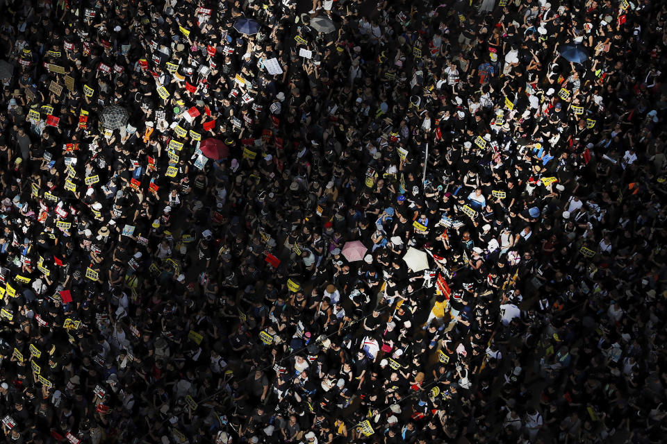 Beams of sunlight are cast on protesters as they march during a rally in Hong Kong, Monday, July 1, 2019. Combative protesters tried to break into the Hong Kong legislature Monday as a crowd of thousands prepared to start a march in that direction on the 22nd anniversary of the former British colony's return to China. (AP Photo/Kin Cheung)