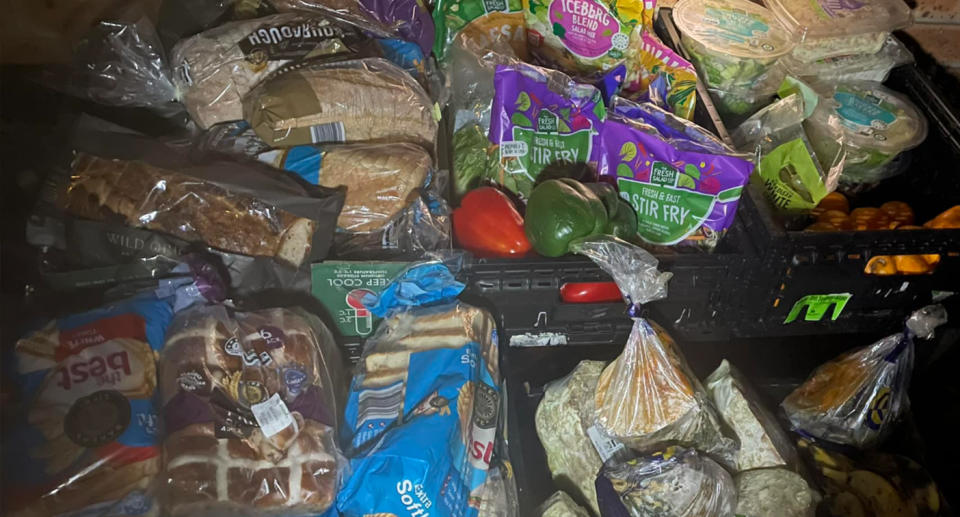 Loaves of bread and vegetables stacked in crates. 