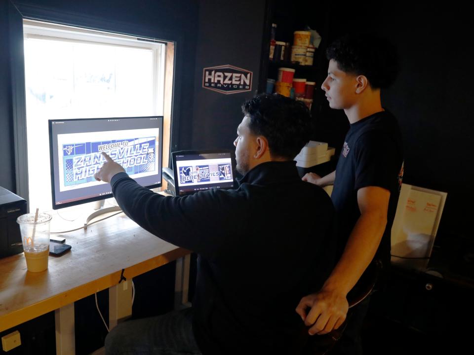 Anthony Smith, left, shows brother Caleb Smith the proof of the new security wrap at Zanesville High School. The Zanesville natives started We Wrap Graphics in 2021 and have performed multiple vinyl wrapping and other projects in the area.