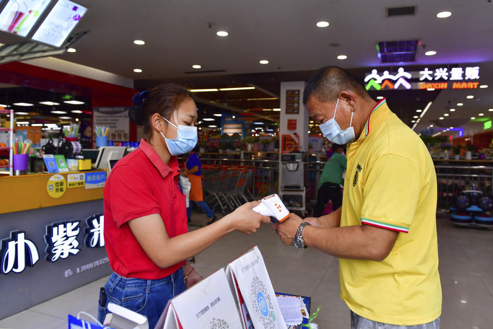 In this photo released by Xinhua News Agency, a resident goes through health screening to enter a supermarket in Ruili, southwestern China's Yunnan Province, on April 1, 2021. COVID-19 cases in the southwestern Chinese city of Ruili bordering on Myanmar have now topped 100 on Monday, April 5, 2021. That comes as authorities have launched an aggressive campaign to vaccinate all 300,000 residents of the city, whose outbreak is something of an anomaly in a country that has all-but eliminated local transmission of the virus.(Chen Xinbo/Xinhua via AP)