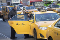 Passengers get into a taxi, Wednesday, Jan. 29, 2020, in New York. A task force studying New York City's struggling taxi industry called Friday for “mission-driven” investors to help bail out drivers who incurred massive debt once the value of the medallion that allows a person to operate a yellow cab plummeted in the age of Uber and Lyft. (AP Photo/Mark Lennihan)