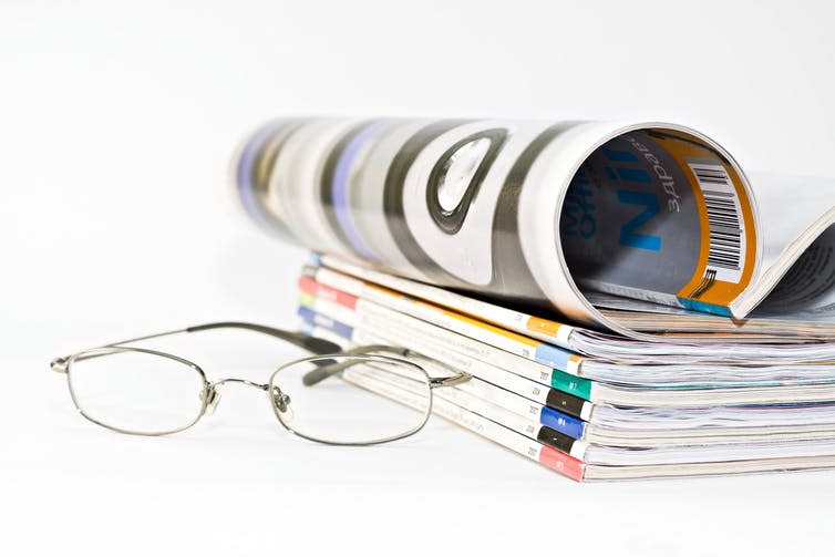 Pile of medical journals next to a pair of spectacles