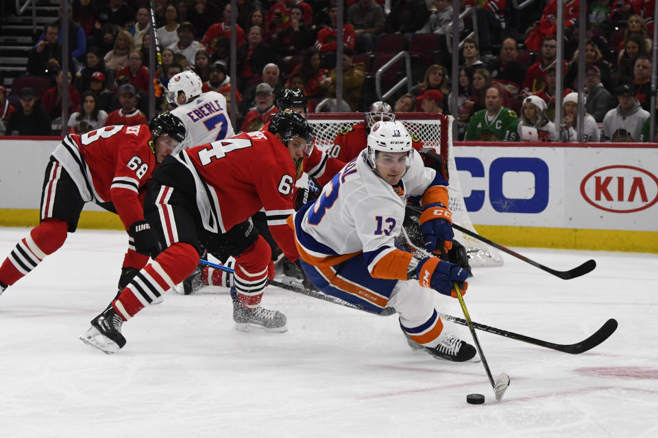 Chicago Blackhawks center David Kampf (64) and New York Islanders center Mathew Barzal (13) compete for the puck during the first period of an NHL hockey game Friday, Dec. 27, 2019, in Chicago. (AP Photo/Matt Marton)