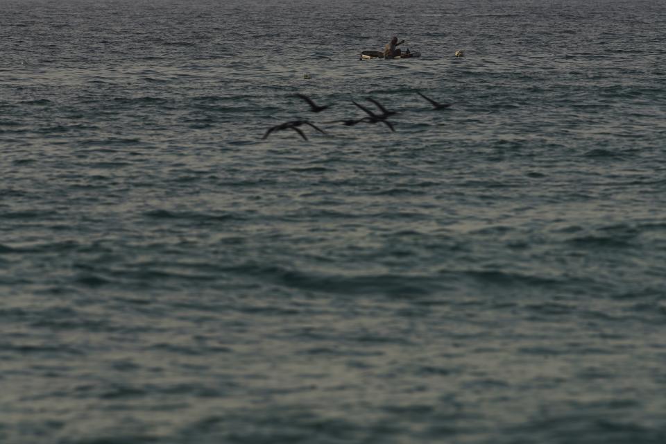 A fisherman casts his nets off Fujairah, United Arab Emirates, Wednesday, Aug. 4, 2021. The British navy warned of a "potential hijack" of another ship off the coast of the United Arab Emirates in the Gulf of Oman near Fujairah on Tuesday, though the circumstances remain unclear. (AP Photo/Jon Gambrell)