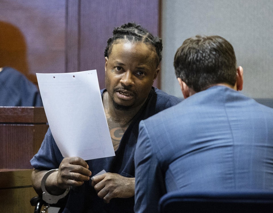 FILE - Lee Frank Wilson talks to his attorney Josh Tomsheck during his court appearance on March 3, 2022, in Las Vegas. Eleven attempted murder charges were dropped and a 44-year-old ex-convict pleaded guilty to a single felony charge in a deadly shootout that authorities say involved at least five shooters at a Las Vegas lounge. Wilson admitted Wednesday, May 18, 2022, he was a felon in possession of a prohibited firearm. (Bizuayehu Tesfaye/Las Vegas Review-Journal via AP, File)