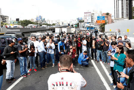 Members of the media wait for Juan Guaido, who many nations have recognized as the country's rightful interim ruler, to pass by on the motorway, in Caracas, Venezuela February 21, 2019. REUTERS/Carlos Jasso