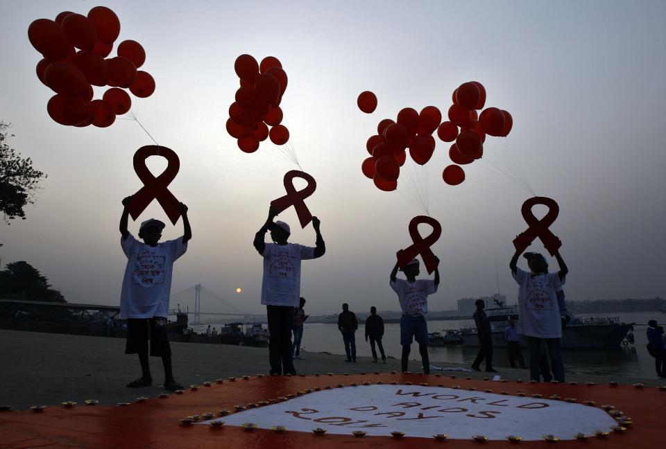 Children display ribbon cut-outs tied to balloons during an HIV/AIDS awareness campaign to mark World AIDS Day in Kolkata December 1, 2014. The world has finally reached "the beginning of the end" of the AIDS pandemic that has infected and killed millions in the past 30 years, according to a leading campaign group fighting HIV. United Nations data show that in 2013, 35 million people were living with HIV, 2.1 million people were newly infected with the virus and some 1.5 million people died of AIDS. By far the greatest part of the HIV/AIDS burden is in sub-Saharan Africa. REUTERS/Rupak De Chowdhuri (INDIA - Tags: HEALTH SOCIETY)