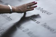 An attendee touches the stone with names of victims at the 9/11 Memorial during ceremonies marking the 12th anniversary of the 9/11 attacks on the World Trade Center in New York September 11, 2013. REUTERS/Chris Pedota/Pool