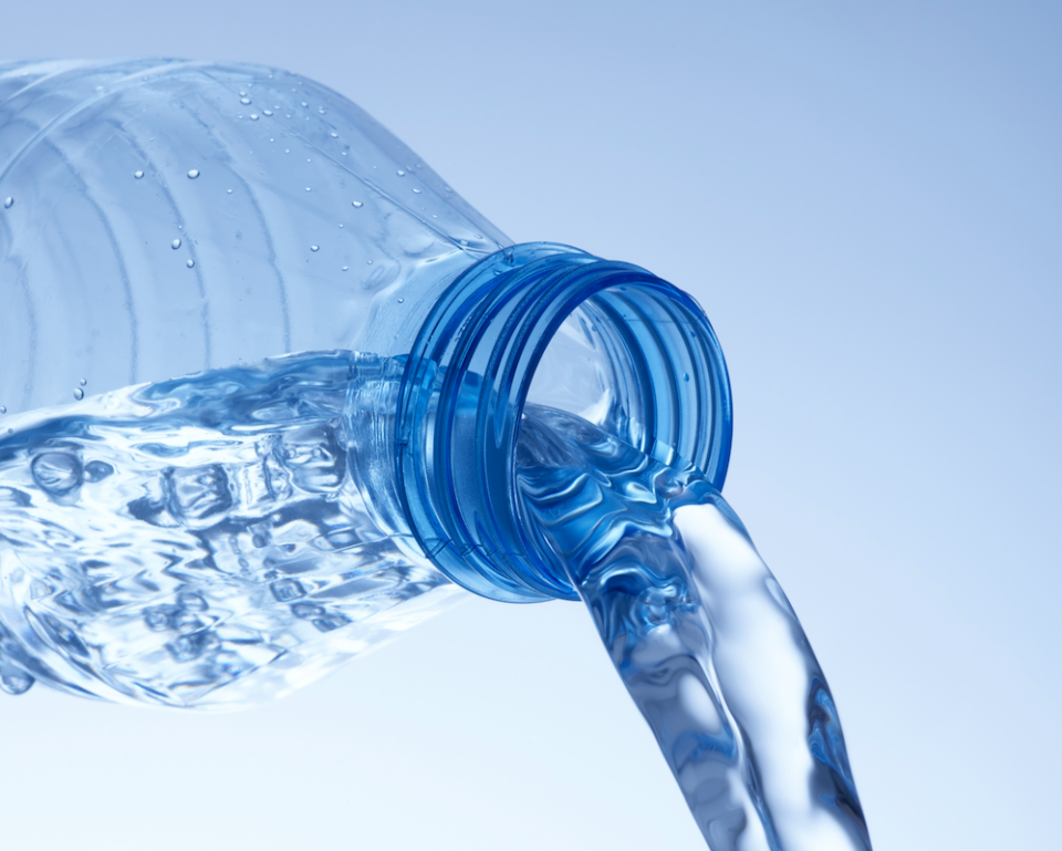 A plastic water bottle being tipped, pouring out water