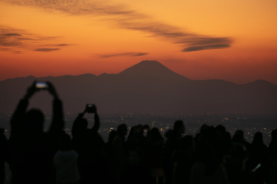 FILE- Visitors take pictures of Mount Fuji from Shibuya Sky observation deck Monday, Jan. 20, 2020, in the Shibuya district of Tokyo. (AP Photo/Jae C. Hong, File)