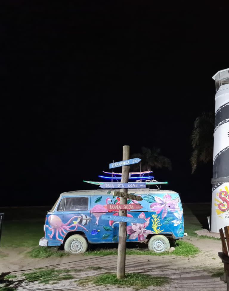 La van estilo surfer y el faro, detrás, una opción para no poner el clásico cartel con nombre del lugar, en este caso Malloys en la costa de Martínez 