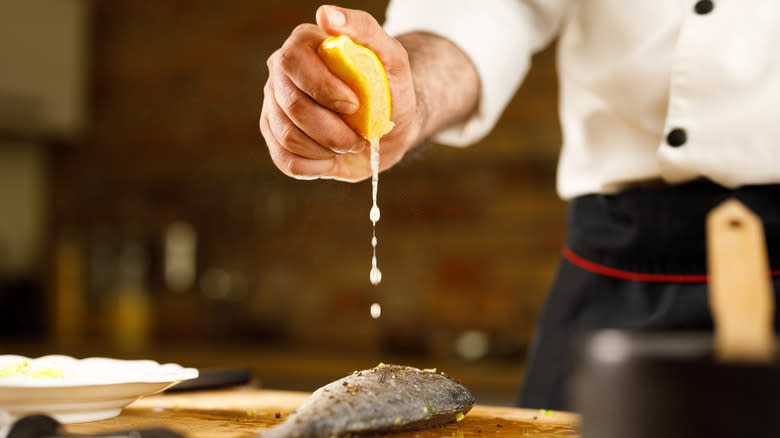 A chef squeezing a lemon onto a fish