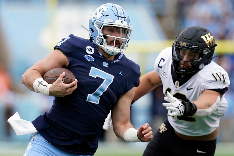 North Carolina quarterback Sam Howell (7) runs the ball while Wake Forest defensive back Luke Masterson (12) reaches for the tackle during the first half of an NCAA college football game in Chapel Hill, N.C., Saturday, Nov. 6, 2021. (AP Photo/Gerry Broome)