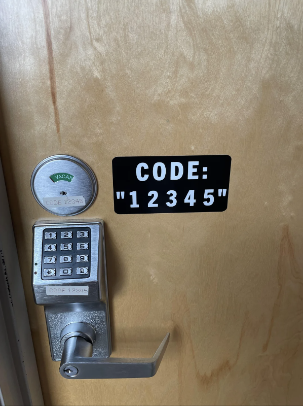 Door with a keypad lock, a sign displaying "CODE: 12345," and an indicator showing "VACANT."