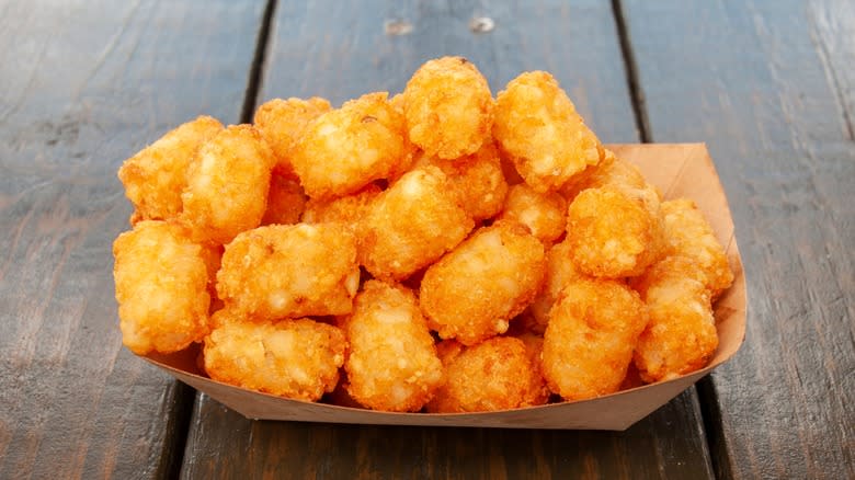 Cardboard boat of tater tots on wooden table