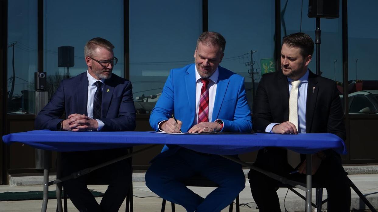 Federal Health Minister Mark Holland, centre, signs a health-care funding agreement in Regina on Monday, accompanied by Sask. Health Minister Everett Hindley, left, and Tim McLeod, the Sask. minister of mental health and addictions, seniors and rural and remote health. (Olivier Jodouin/CBC - image credit)