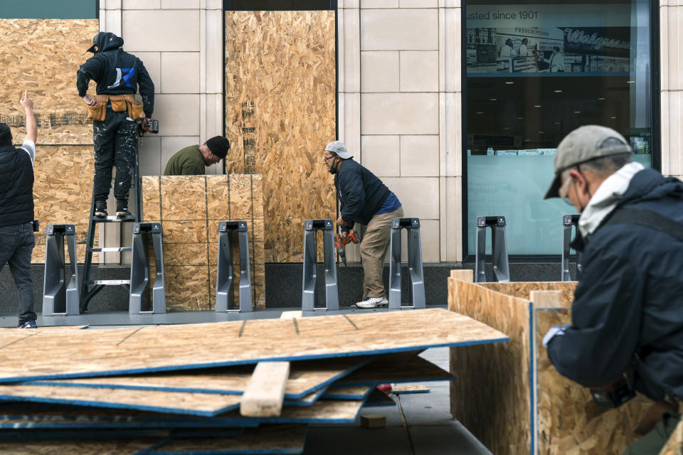 Workers with Baguer Construction LLC board up a Walgreens on U Street NW, Friday, Oct. 30, 2020, in Washington. The site manager said they had been hired to put protective coverings on several Walgreens throughout the city ahead of the election. (AP Photo/Jacquelyn Martin)