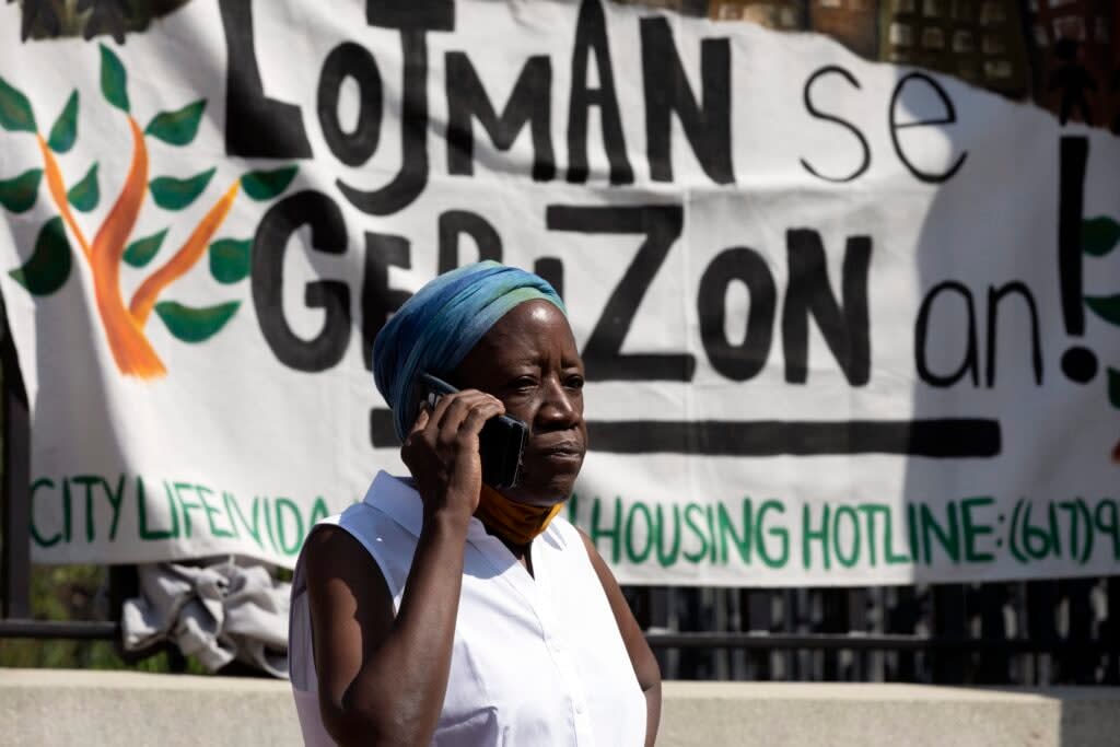 A woman in front of a sign in Haitian Creole during a news conference held by housing justice groups to protest evictions, Friday, July 30, 2021, in Boston. (AP Photo/Michael Dwyer)