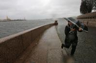 A woman with an umbrella walks opposite the Peter and Paul fortress during strong storm winds and rain in central St. Petersburg October 29, 2013. REUTERS/Alexander Demianchuk (RUSSIA - Tags: ENVIRONMENT)