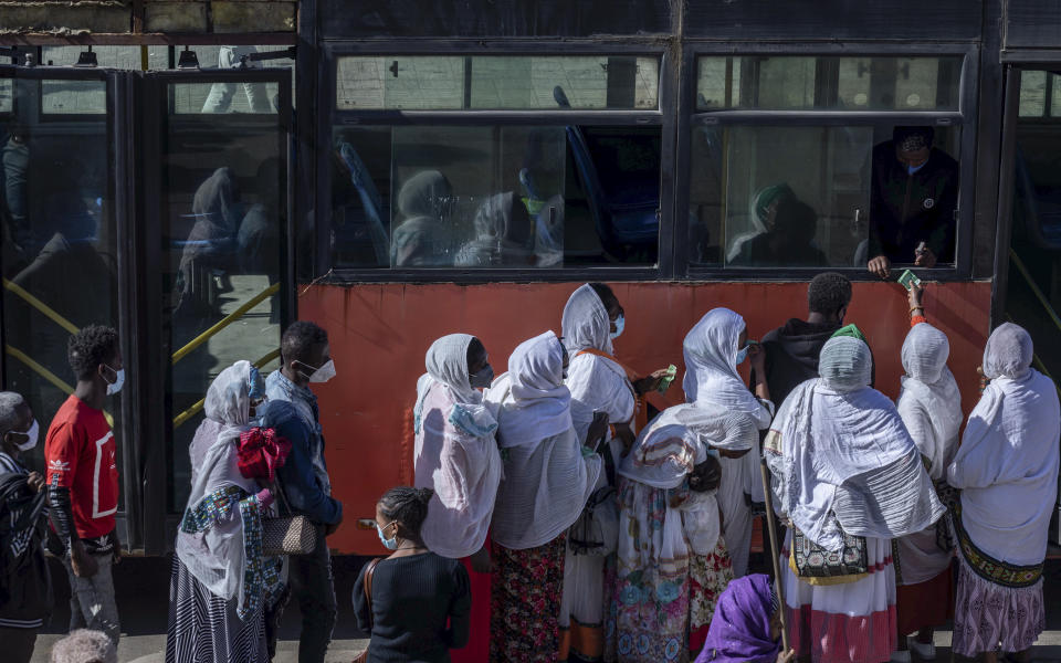 Passengers queue to get on a bus in the capital Addis Ababa, Ethiopia Friday, Nov. 6, 2020. Ethiopia's prime minister says airstrikes have been carried out against the forces of the country's Tigray region, asserting that the strikes in multiple locations "completely destroyed rockets and other heavy weapons." (AP Photo/Mulugeta Ayene)