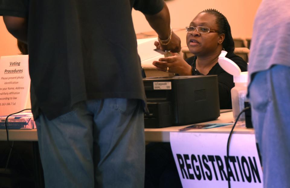 Poll worker Jackie Morales checks a voter's identification on Tuesday, March 15, 2016, at Church of the Nazarene in Fayetteville. That was the last time photo ID was required in a North Carolina election. Photo ID will be required again starting with the 2023 municipal elections.