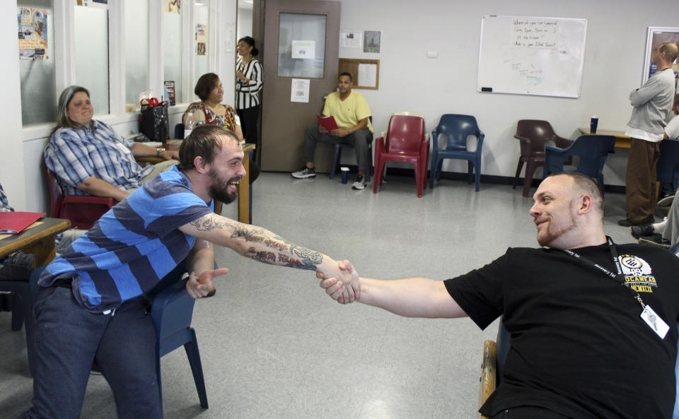 In this Aug. 5, 2019 photo, Israel Rivera, left, and Michael Manning greet each other during a group counseling session at the Hampden County Sheriff's Department's minimum security, residential treatment facility in Springfield, Mass. The county jail is marking one year of treating men civilly committed for substance abuse reasons. Sheriff Thomas Cocchi and his supporters have said the program, one of just three in the state treating civilly committed men and the only in western Massachusetts, can play a key role in efforts to curb the Springfield area's opioid problem. But civil rights group want the practice of imprisoning men for addiction treatment ended. (AP Photo/Philip Marcelo)