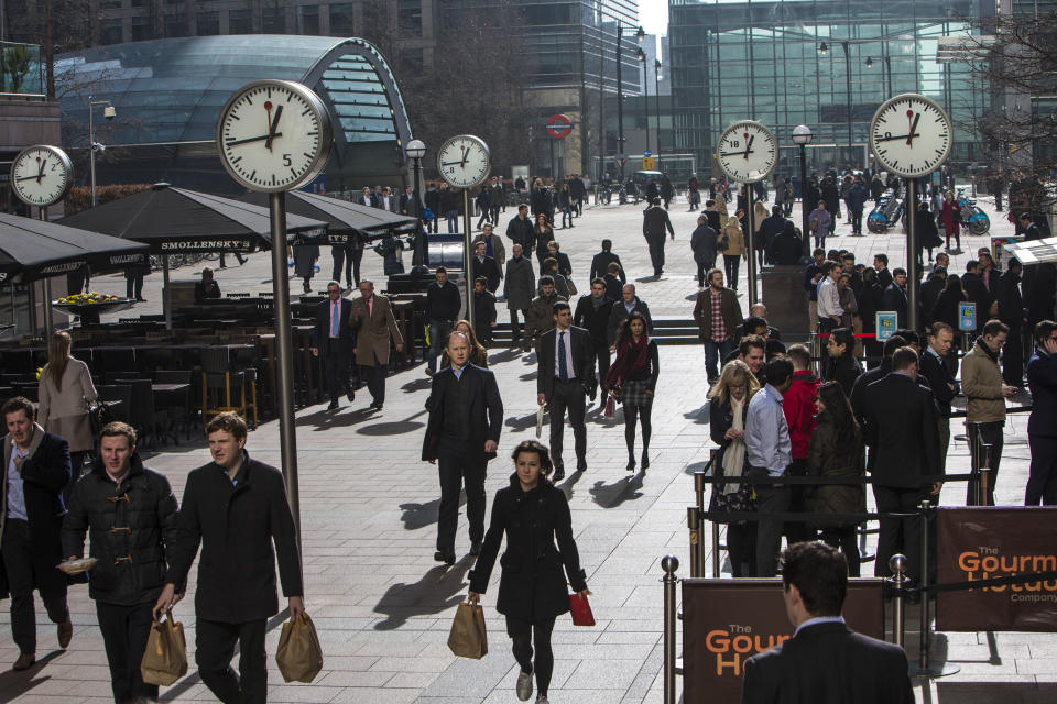 City workers walk under the clocks of Nash Court in Reuters Plaza to commute to work in Canary Wharf financial district London, England, United Kingdom. (Photo by In Pictures Ltd./Corbis via Getty Images)