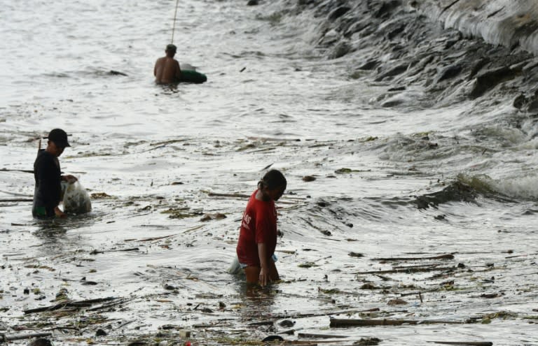 People collect recyclable materials washed ashore, after Typhoon Sarika passed north of the Philippines capital overnight